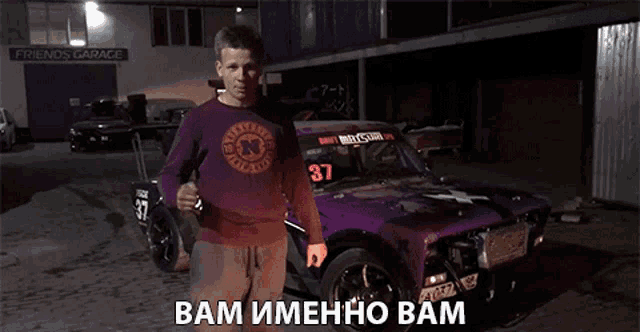 a man standing in front of a purple car with the number 37 on the windshield
