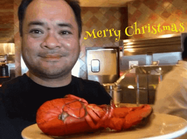a man is holding a plate of lobster with a merry christmas sign in the background
