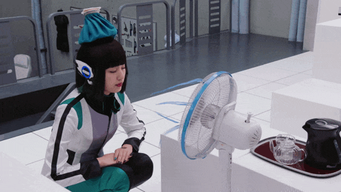 a woman in a costume sits in front of a fan