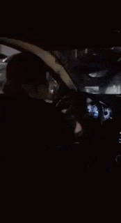 a person is driving a car at night with a steering wheel visible .