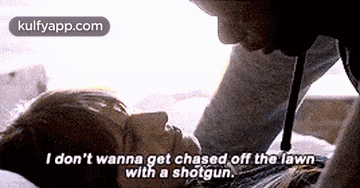 a man is kissing a woman on the forehead while laying on a bed with a shotgun .