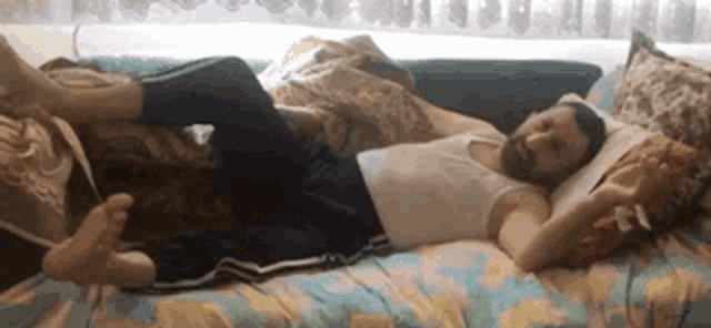 a man with a beard is laying on a couch with his feet up .