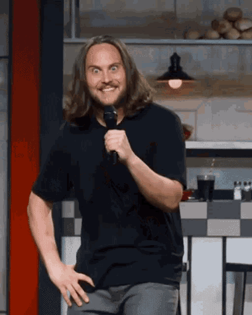 a man with long hair is holding a microphone and making a funny face