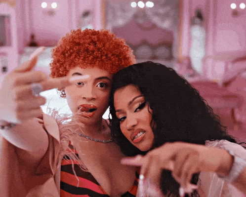 two women are posing for a picture with one pointing at the camera