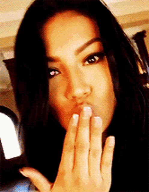 a woman blows a kiss with her hand