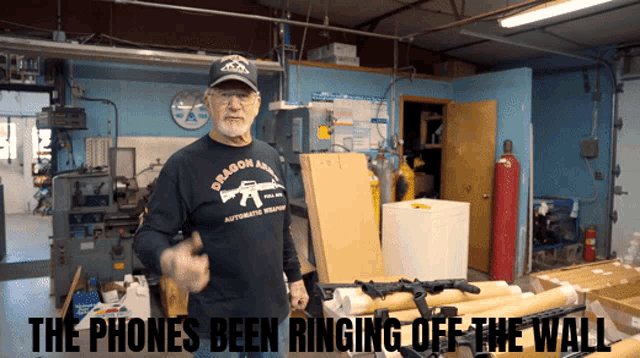 a man wearing a black shirt that says deason armory holds a gun