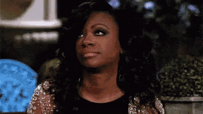 a woman is making a funny face while wearing a black dress and a silver jacket .
