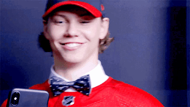 a man wearing a red hat and bow tie is holding a phone