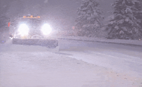 a snow plow is driving down a snowy road