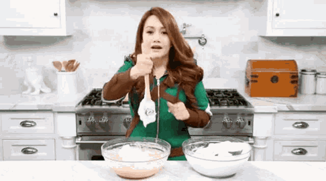 a woman is standing in a kitchen with two bowls of food on the counter
