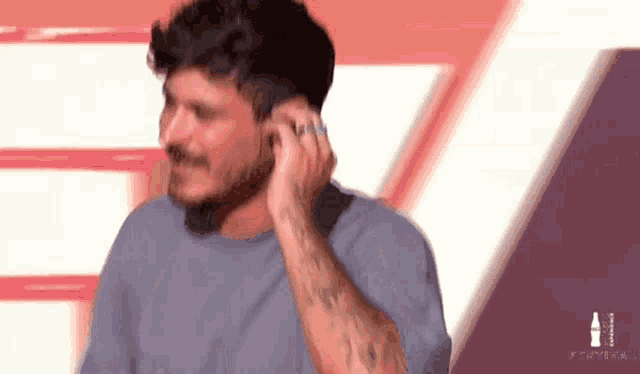 a man with a tattoo on his arm is wearing ear buds .