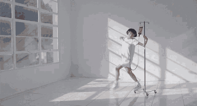 a woman in a white dress is dancing next to an iv drip