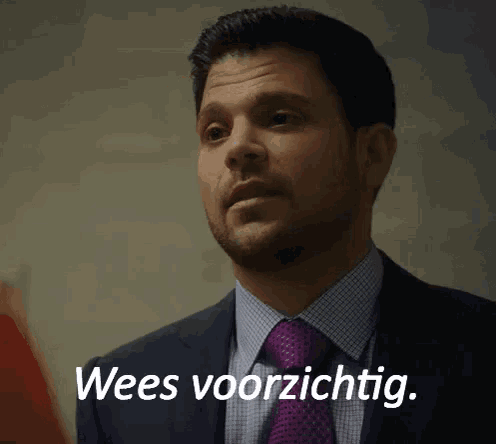 a man in a suit and tie is saying " wees voorzichtig "