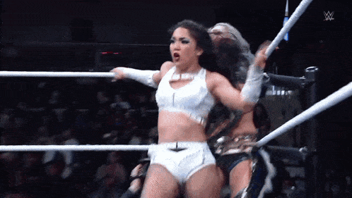 two women are wrestling in a ring and one of them is holding a rope .