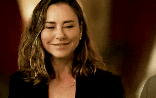 a woman is smiling with her eyes closed and wearing earrings