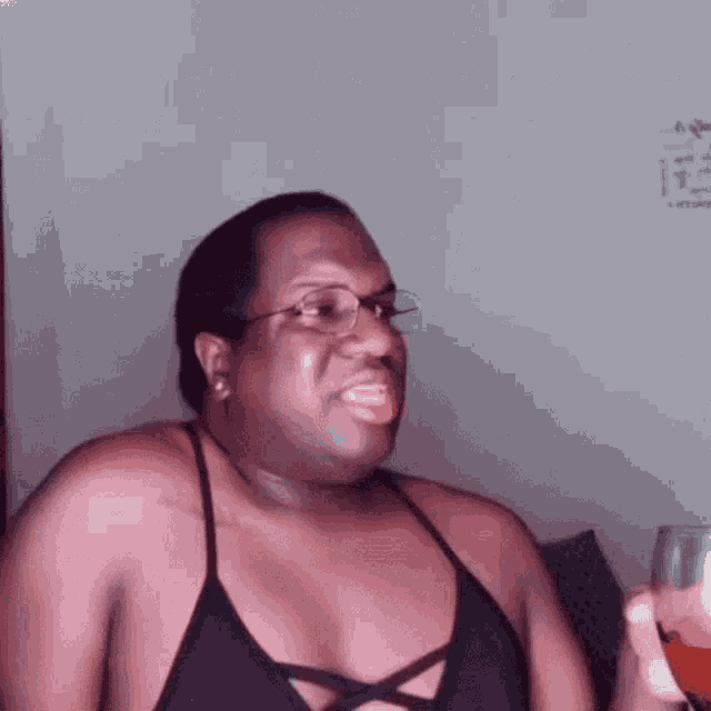 a man wearing glasses and a black tank top is smiling