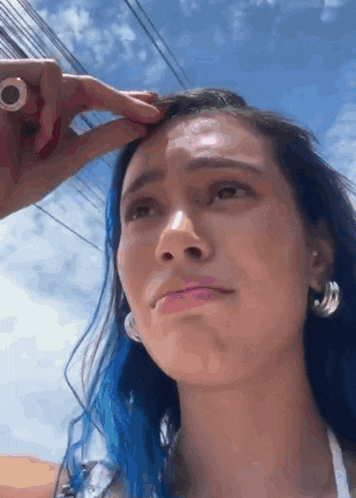 a woman with blue hair is crying while someone holds her hair