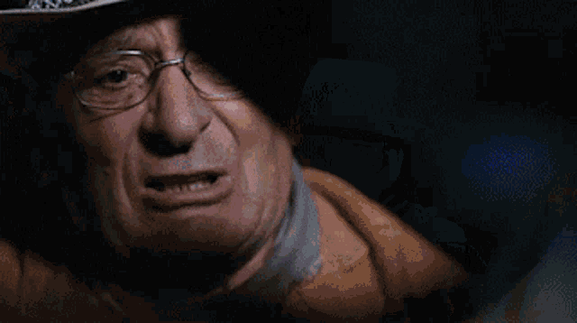 a man wearing a cowboy hat and glasses is crying .