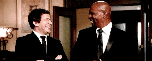 two men in suits and ties are standing next to each other and laughing .