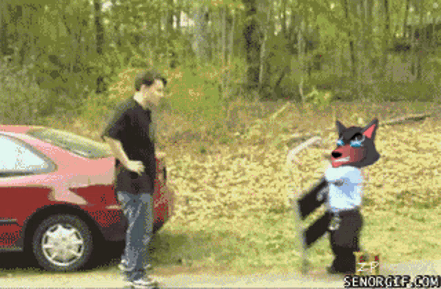 a man standing next to a red car with a picture of a wolf with sunglasses on