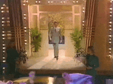 a man in a suit and tie walks down a stage