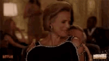 a woman in a black dress is sitting next to a man in a room .