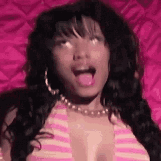 a woman is sticking her tongue out while wearing a pink and white striped top .