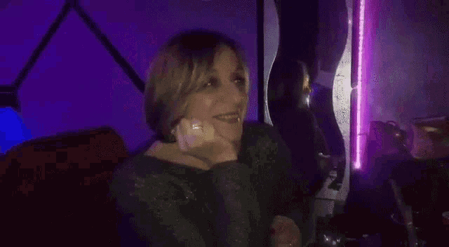 a woman is making a peace sign with her hands while sitting in a dark room .