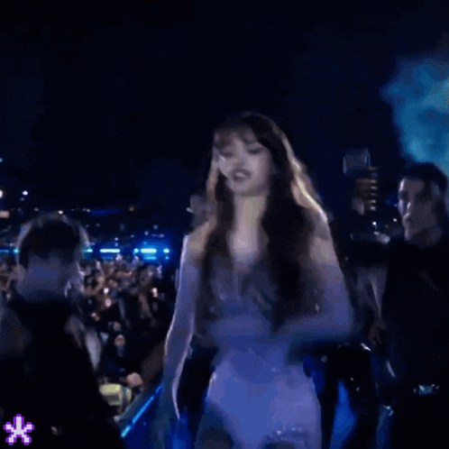 a woman in a white dress is dancing in front of a crowd at a concert .