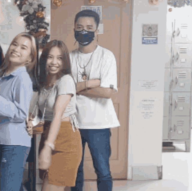 a man wearing a face mask is standing next to two women .