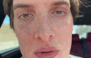 a close up of a man 's face while sitting in a car with his mouth open .