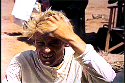 a man wearing a white shirt is scratching his head