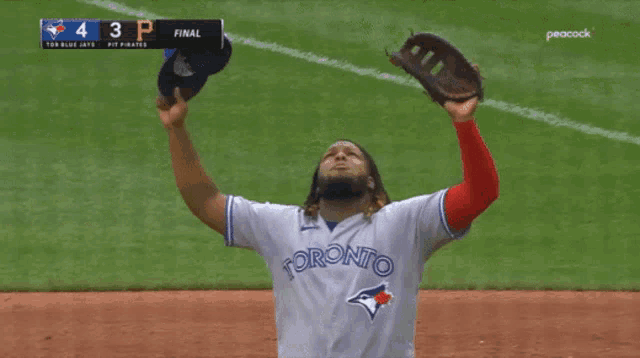 a toronto blue jays baseball player throws his cap in the air