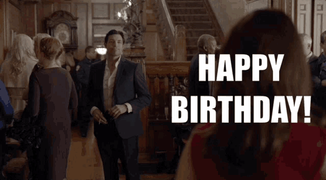 a man in a suit and a woman in a red dress are standing in front of a sign that reads happy birthday