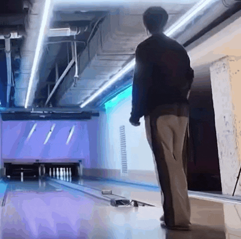 a man is standing on the edge of a bowling alley .