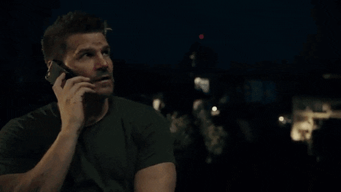 a man in a green shirt is talking on a cell phone .