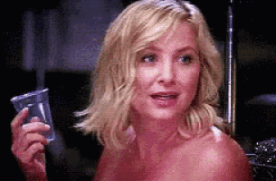 a naked woman is holding a plastic cup and smiling .