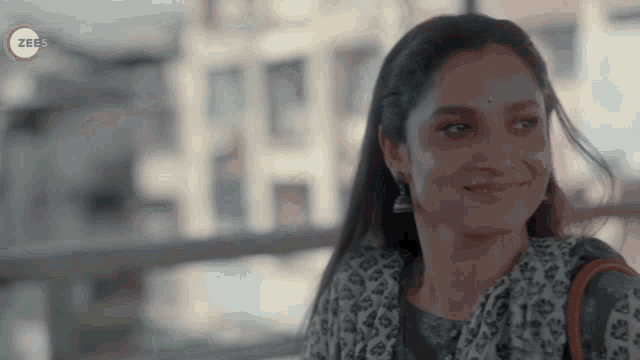 a woman is smiling in front of a screen that says zee5 on it