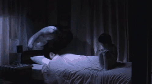 a woman is laying on a bed with a ghost coming out of it