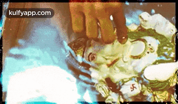 a picture of a person washing a statue of ganesha in a bowl of water .