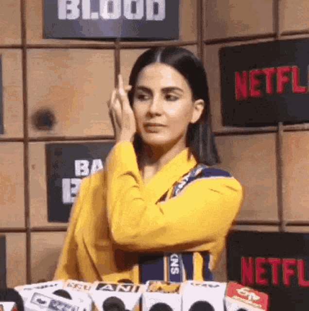 a woman in a yellow shirt is standing in front of a netflix sign