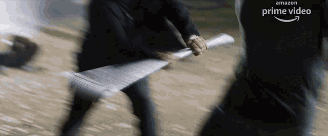 a blurred image of a man holding a sword with the amazon prime video logo in the background