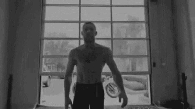 a shirtless man is standing in front of a garage door .