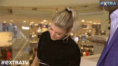 a woman in a ponytail is standing in front of a man in a suit and a sign that says extratv