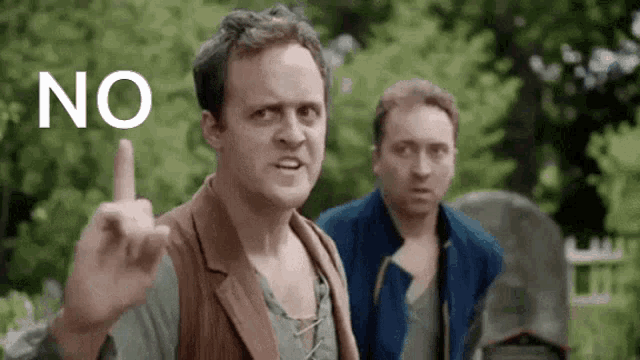 two men are standing next to each other and one of them is making a rude gesture with his finger .