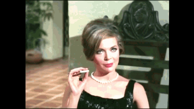 a woman in a black dress is holding a cigarette