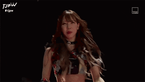 a woman is standing in front of a crowd of people in a dark room .
