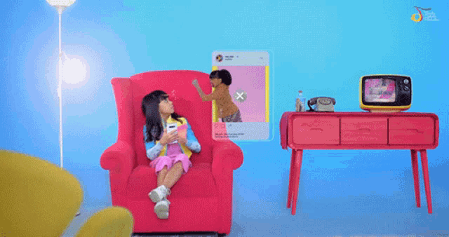 a girl sits in a red chair with a picture of a girl on the wall