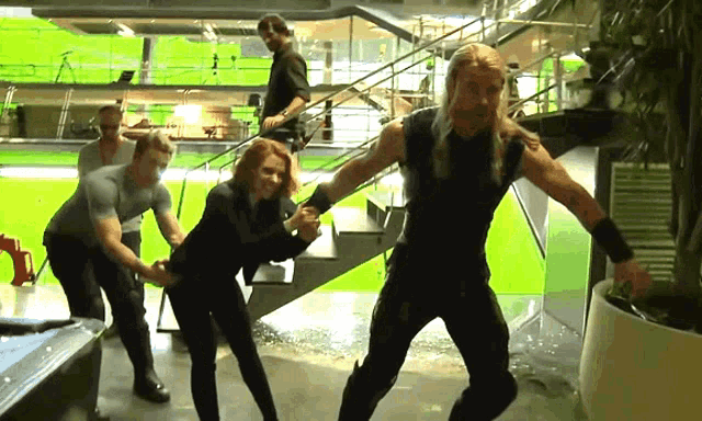 a group of people are standing in a room with a green screen in the background
