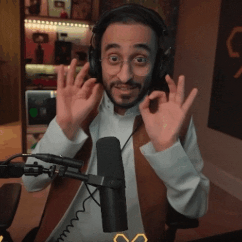 a man wearing headphones and glasses giving an ok sign